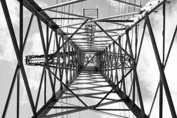 Lattice-type steel tower as a part of high-voltage line. Photo from below with perspective effect. Overhead power line details