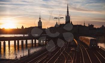 Evening cityscape with Metro train crossing the bridge of Gamla Stan, Stockholm, Sweden