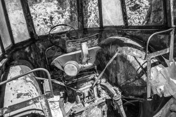 Old abandoned rusted tractor cabin interior, black and white retro style photo