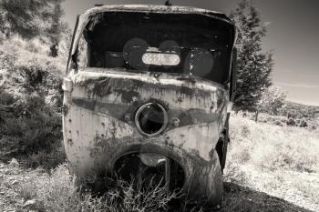 Abandoned rusted body of three-wheeled light commercial vehicle, old style filter effect, monochrome retro photo