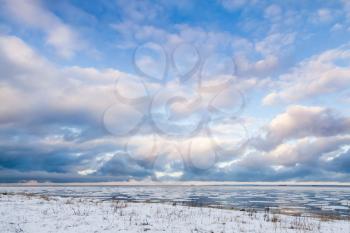 Winter coastal landscape with ice fragments under colorful cloudy sky. Gulf of Finland, Russia