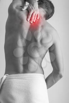 Young adult Caucasian man with backache. Black and white stylized photo with red local pain spot over back