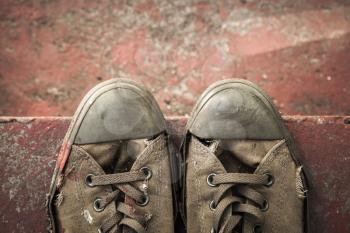 Old sneakers stand on red concrete stairs, closeup photo, top view