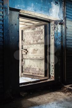 Abstract dark grungy industrial interior with blue rusted metal wall and open heavy steel door
