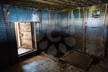 Abstract dark grungy industrial interior with blue rusted metal walls and open heavy steel door