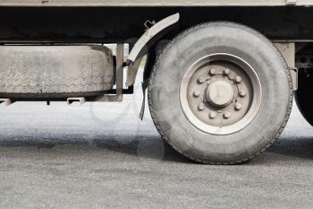 Dirty wheels of lorry on gray asphalt road