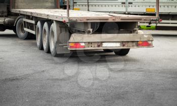 Rear fragment with taillight of empty truck cargo trailer on asphalt road