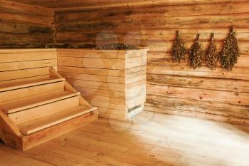 Empty wooden interior of Russian sauna with brooms on the wall