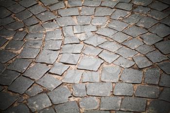 Dark gray cobble road, stone street pavement, background photo with selective focus and vignette effect