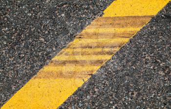 Yellow dividing line with tire tracks over it, highway road marking. Abstract transportation background