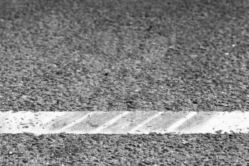 Dividing line with tire tracks over it, highway road marking fragment. Abstract transportation background