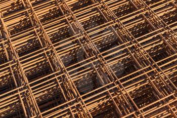Abstract construction background with stacked rusted reinforcing mesh, photo with selective focus