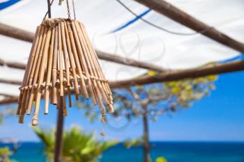 Outdoor chandelier made of bamboo tubes hanging on white sun shading canopy, balcony terrace. Zakynthos island, Greece