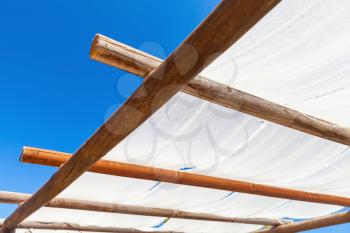 Shading canopy made of wooden beams and white fabric