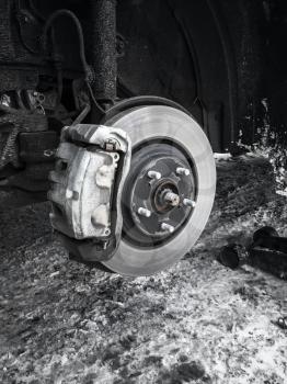 Replacing wheel on modern car, black and white photo of rotor disk with brake, selective focus