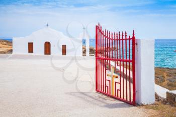 Agios Nikolaos. Open red gate of small white Orthodox church