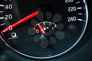 Fuel gauge mounted in round modern car speedometer shows low level of gasoline