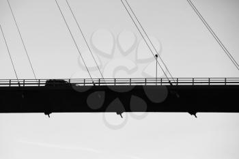 Car drives on modern automotive cable-stayed bridge in Norway, silhouette black and white photo