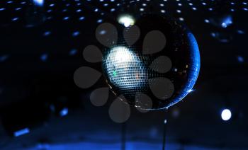 Disco ball with blue rays over dark night club interior background