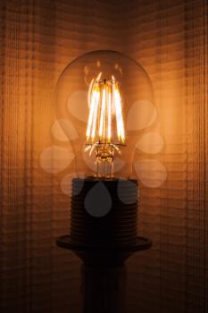Retro tungsten lamp glowing over empty wall, vertical photo with selective focus and shallow DOF