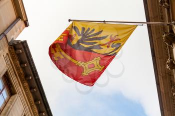 Geneva city, Switzerland.  Flag with coat of arms mounted on old building wall showing the Imperial Eagle and a Key of St. Peter
