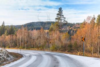 Empty rural Norwegian road covered with snow in autumn season