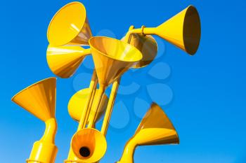 Group of bright yellow loudspeakers over blue sky background, close up