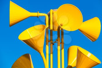 Many bright yellow loudspeakers over blue sky background