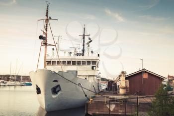 Old white ship moored in port of Kotka, Finland. Vintage toned photo, old style effect