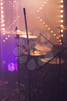 Vertical live music photo background, rock drum set  with cymbals and colorful blurred stage lights