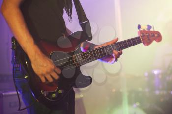 Rock music background, bass guitar player, closeup photo with soft selective focus