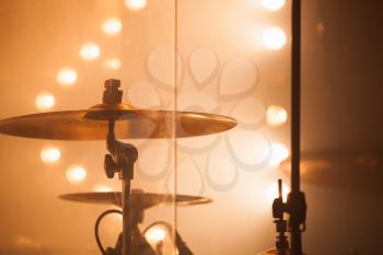 Warm toned musical photo background, cymbals as a part of  rock drum set  over blurred stage lights