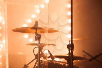 Warm toned musical photo background, rock drum set  with cymbals and blurred stage lights