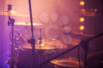 Live rock music background, drummer plays with drumsticks on rock drum set. Closeup photo, soft selective focus