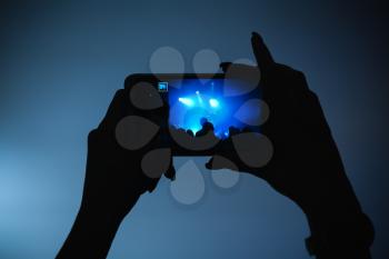 Hands of woman taking photo on her smartphone camera, rock music concert, close-up
