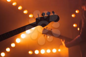 Live music background, electric bass and solo guitar silhouettes, close-up photo with soft selective focus