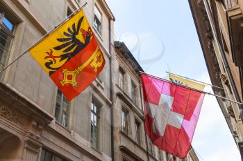 Geneva, Switzerland. Swiss National and City flags mounted on old house wall