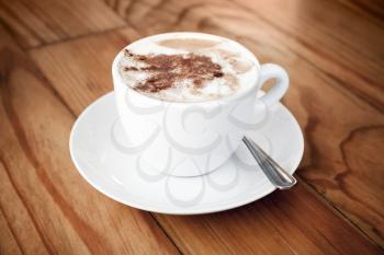 Cappuccino. Cup of coffee with milk foam and cinnamon stands on wooden table