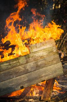 Close-up photo of burning wooden boxes in big bonfire