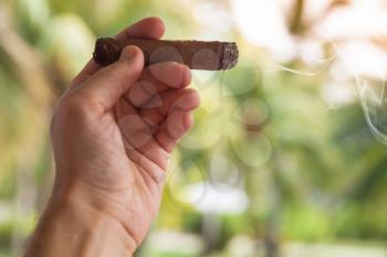 Handmade cigar in male hand, closeup photo with selective focus