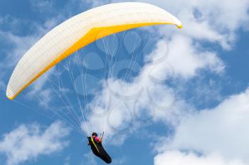 Amateur paraglider flying in blue sky with clouds
