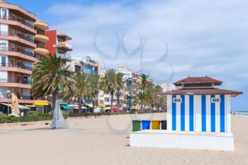 Coastal street and wide public sandy beach of Calafell resort town in sunny summer day. Tarragona region, Catalonia, Spain