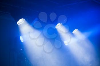 Spot lights with blue rays in smoky dark, stage illumination equipment