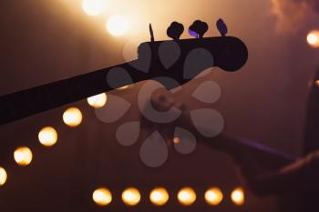 Live music background, electric bass and solo guitar silhouettes, closeup photo with soft selective focus
