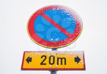 No parking zone, round road sign on metal pole with snow and frost