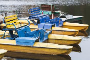 Old yellow blue promenade catamarans moored on still lake coast in Russia
