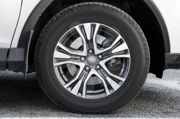 Fragment of white modern car with wheel on steel disc, closeup photo