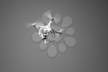 White quadcopter, compact drone controlled by wireless remote, black and white photo