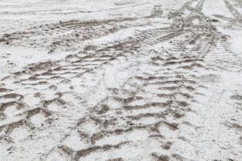 Tractor tire tracks pattern on sandy white ground in winter, abstract transportation background photo, selective focus