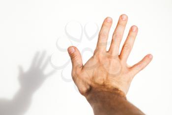 Male hand over white wall background with soft shadow, close up photo with selective focus